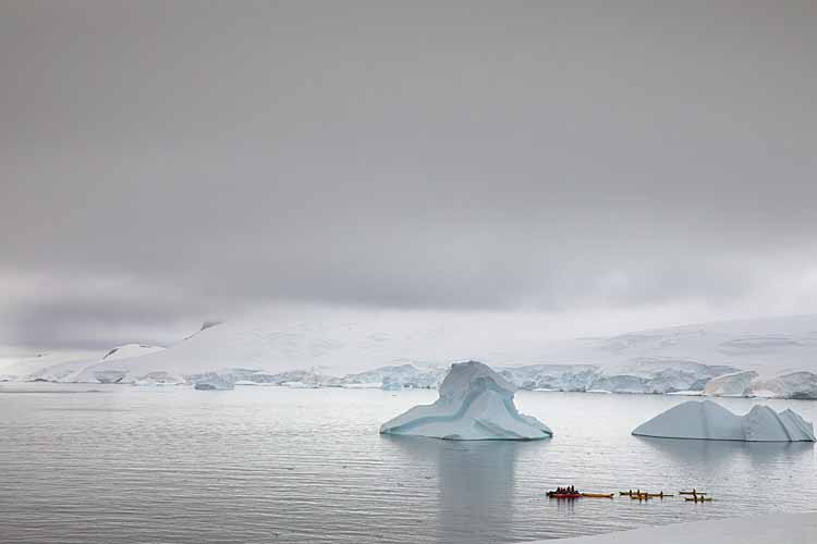 Tourists in kayaks on Antarctic Peninsula, Lemaire Channel.