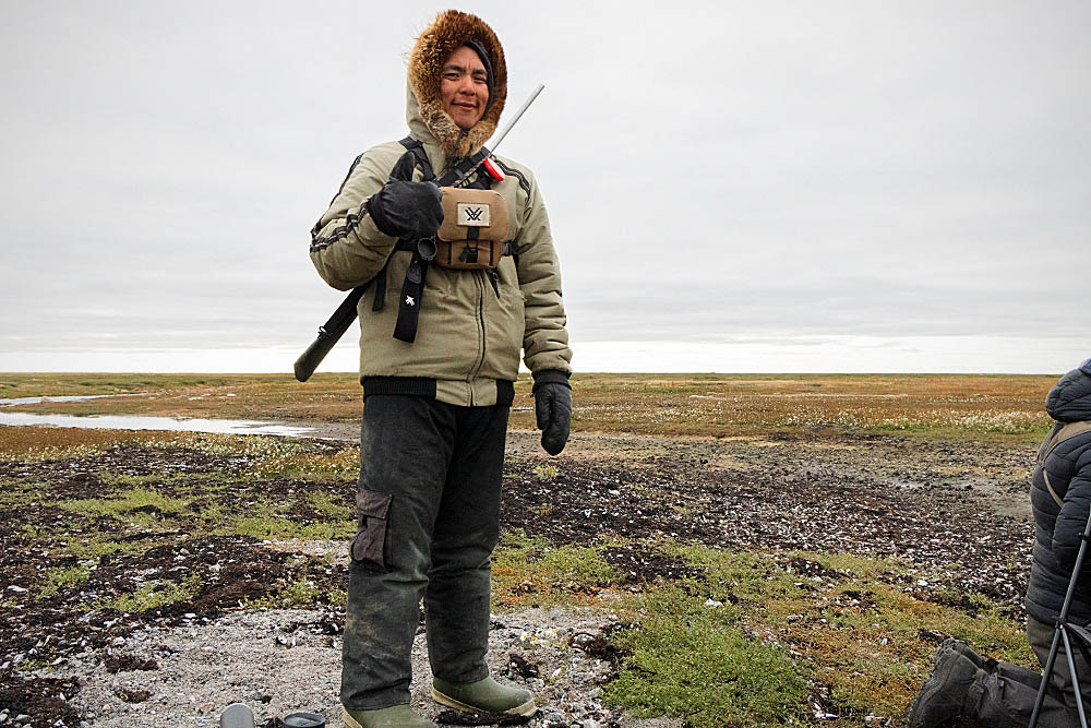 Inuit guide on the shoreline between the arctic tundra and Hudson Bay, Canada, looking for Polar Bear (Ursus maritimus)