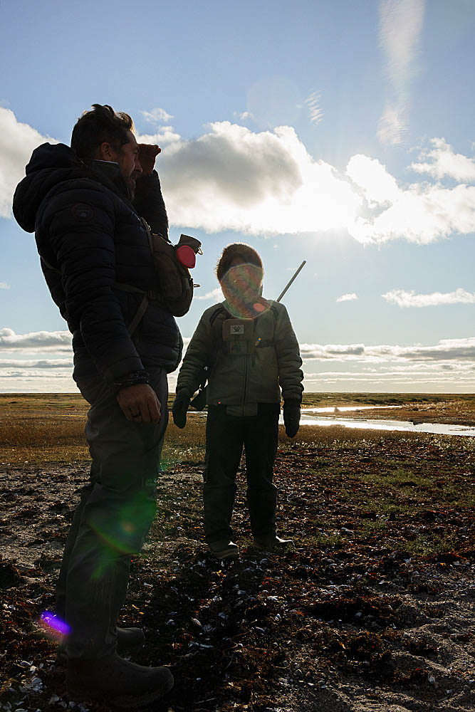 Inuit guide on the shoreline between the arctic tundra and Hudson Bay, Canada, looking for Polar Bear (Ursus maritimus)