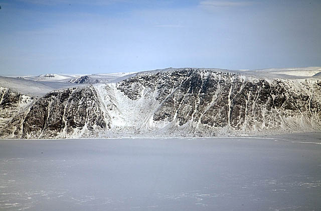 Snow covered seaside cliffs and sea ice.