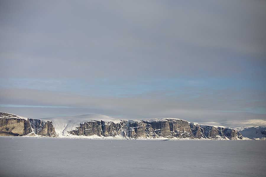 Sea cliffs on edge of frozen bay.