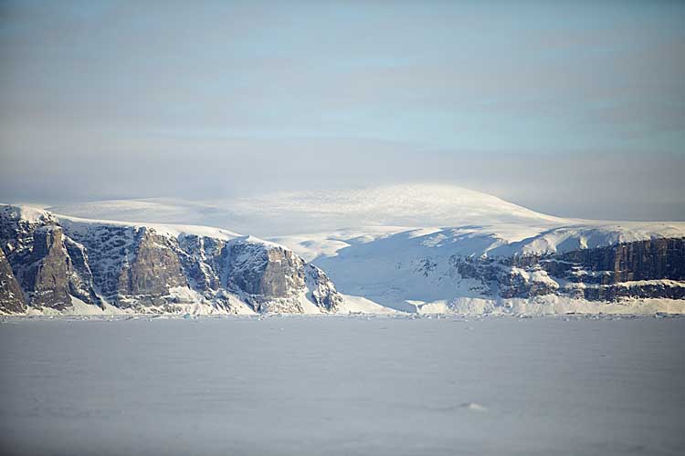 Sea cliffs on edge of frozen bay.