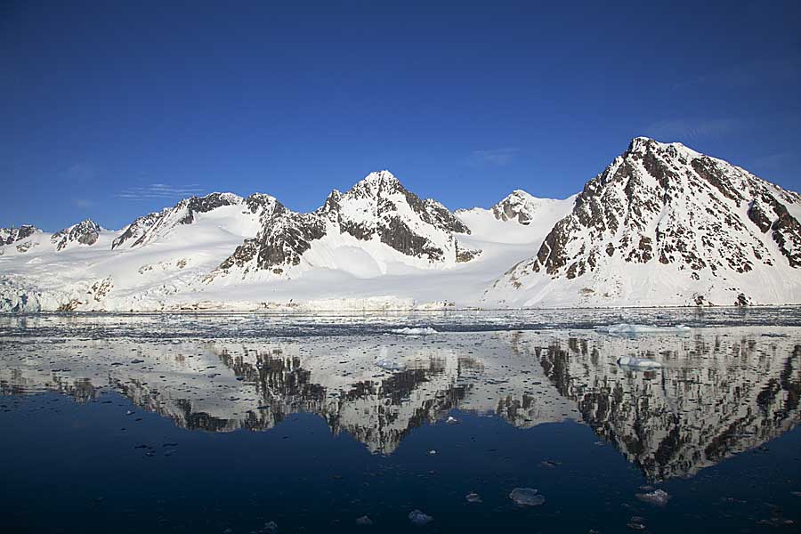 Coastal hills and cliffs reflected in arctic bay.